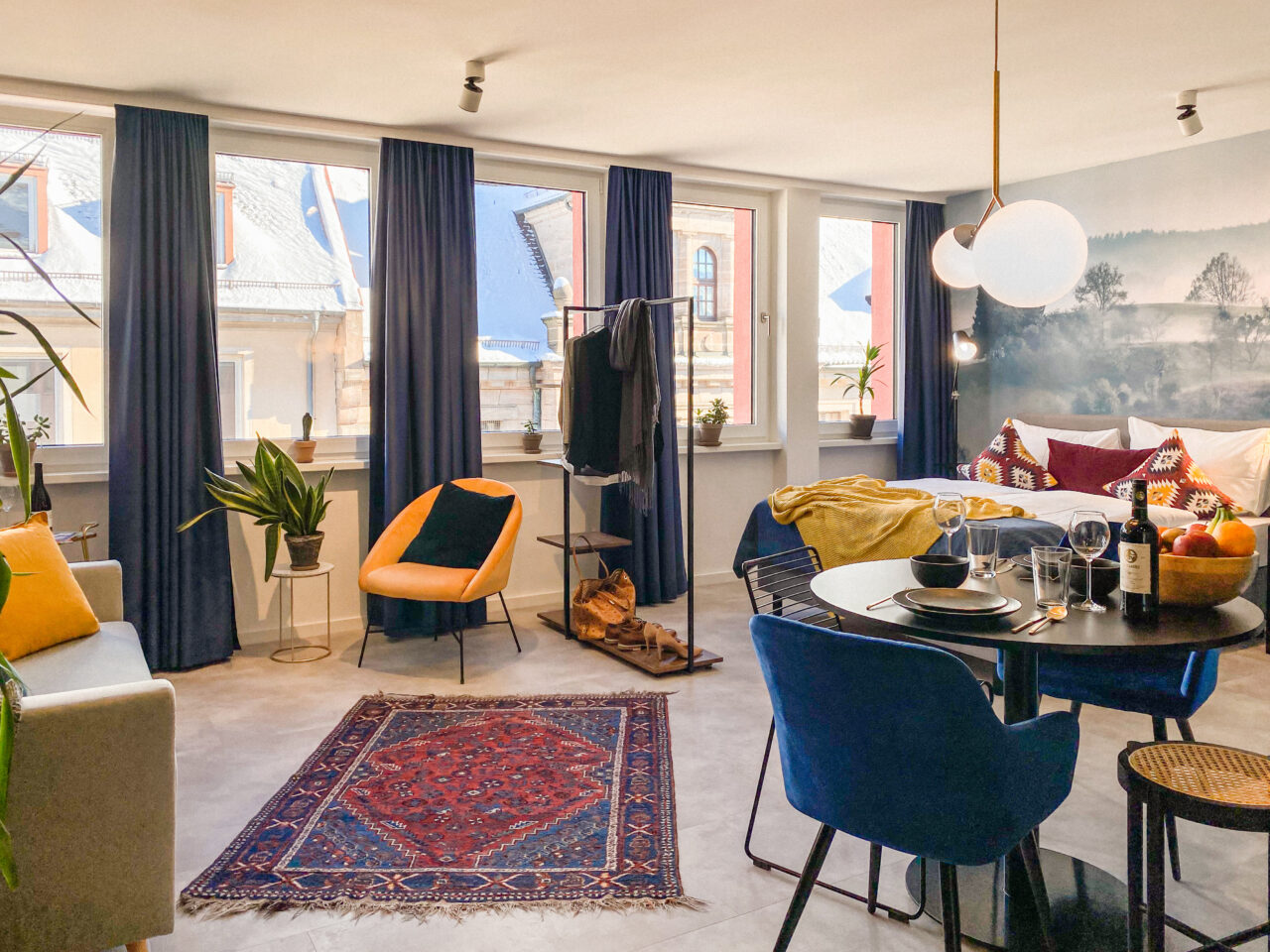 Essplatz mit blauen Stühlen, gedecktem Tisch und gemustertem Teppich